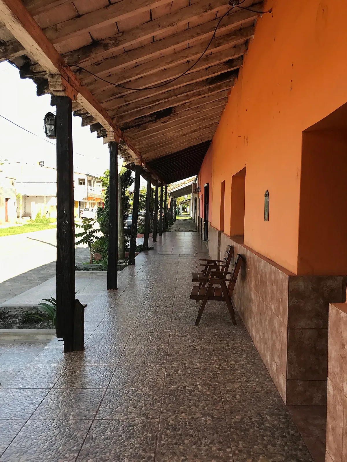 Galería colonial con columnas de madera y piso de baldosas